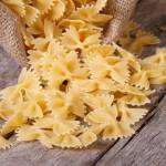 Farfalle pasta dry closeup is scattered on an old table. horizontal
