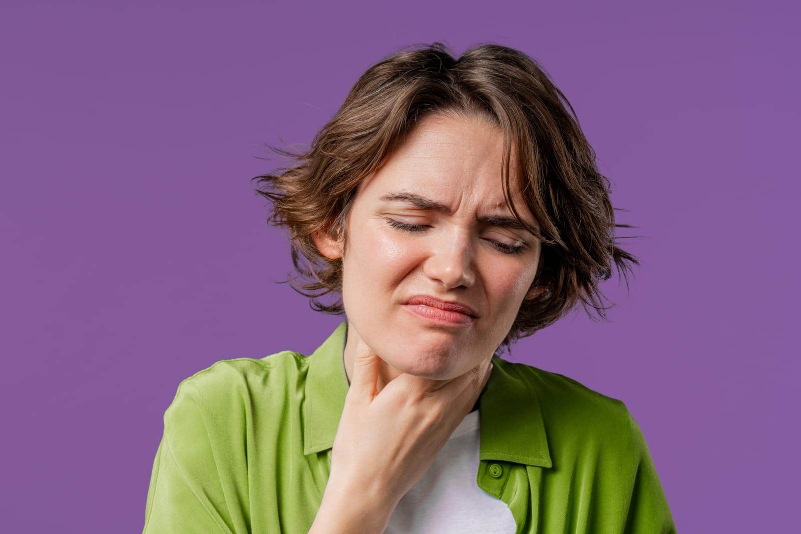 Kobieta z bólem gardła na fioletowym tle.